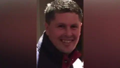 Supplied Mark Coleman. He has short dark hair and is smiling. He is wearing a blue sweatshirt.