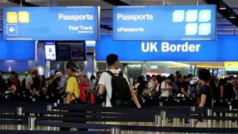 Reuters A busy border control area at Heathrow airport shows travellers queueing up to have their passports inspected, amid signs saying 'UK border' and 'passports', taken in 2017.