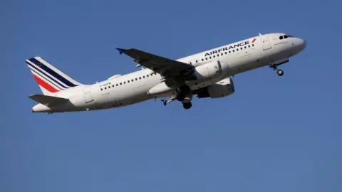 Reuters Air France Airbus A320 airborne above Spain shortly after take-off with red and blue tail livery and white fuselage with Air France logo. The undercarriage is still down.