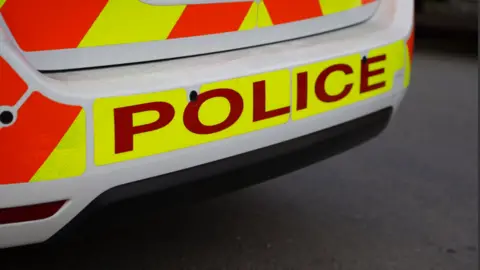 A close up photo of the back of a police car. Text on vehicle reads 'Police'.