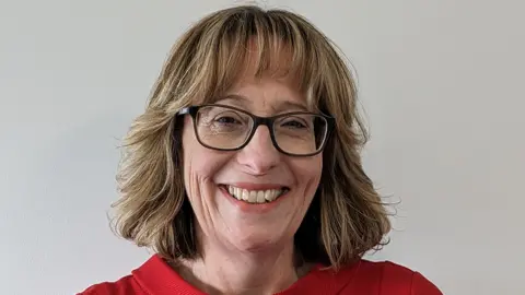 A head and shoulders photos of a woman wearing glasses and a red top