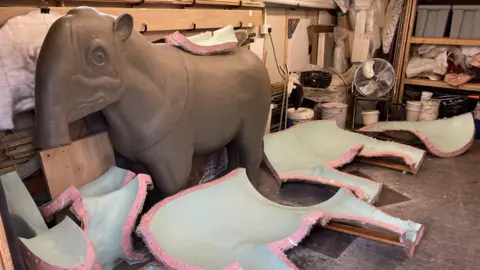 Bob Nicholls Image showing the clay mammal surrounded by piece of the pink and green fibreglass mould.