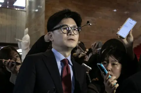 Getty Images Han Dong-hoon cercado por repórteres ao sair da reunião do partido na Assembleia Nacional em Seul