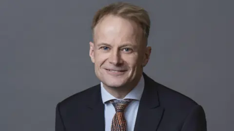 Richard Scolyer smiles at the camera, wearing a suit and tie