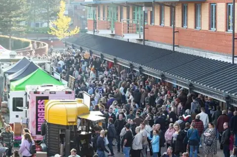 Digbeth Dining Club The Waterfront area of Brierley Hill with crowds queuing outside buildings at mobile food traders. 