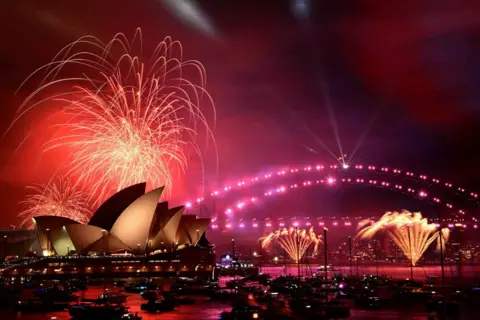 Bianca De Marchi/AAP Image via REUTERS Kembang api pukul 9 malam meledak saat perayaan Malam Tahun Baru di Sydney, Australia, 31 Desember 2024. Kembang api berwarna merah muda terlihat meledak di atas Opera House dan Jembatan Pelabuhan Sydney.