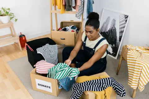 Getty Images A black woman organising clothes into a donations box