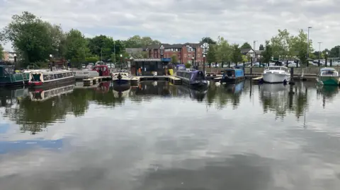 A view of Northwich Marina, with various boats moored up on a cloudy day.