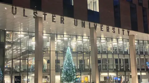 BBC Outside the Ulster University campus. It has a large glass exterior with a tall Christmas tree.
