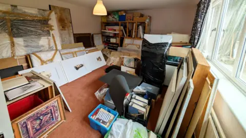 A medium sized suburban room, partially filled with frames and works of art