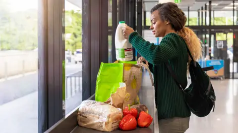 A woman packing groceries into a shopping bag at the supermarket