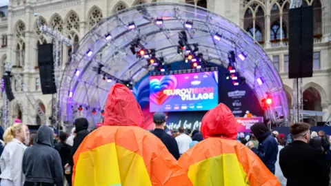 Spectators wearing raincoats in rainbow colours gather at the fan area in front of the City Hall in Vienna on May 14, 2026, prior to the second semi-final of the Eurovision Song Contest (ESC).

