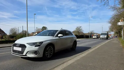 BBC We can see a reasonable amount of traffic on Norwich Road, with a silver Audi in the foreground.