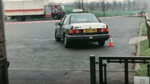 Supplied A photograph taken in 1994 of a crime scene, showing a taxi next to playing fields in Gedling, with a lorry parked in the background