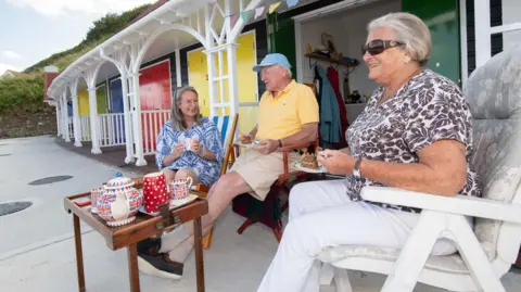 North Yorkshire Council Martin and Jenny Johnson and their daughter, Lisa, drink tea outside one of the new chalets