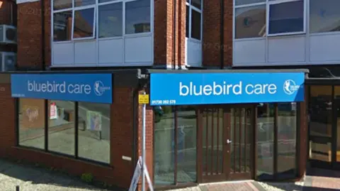 A Bluebird Care office in Petersfield, Hampshire, with the firm's blue sign and logo above the door.