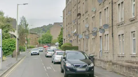 Google A residential street with flats on one side and a park on the other