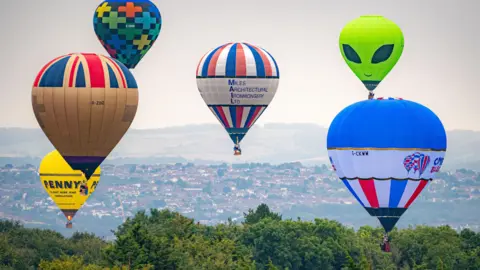 Different coloured balloons fill up the sky on a hazy day