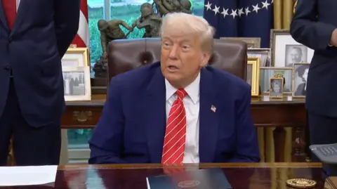Donald Trump sitting in the Oval Office 