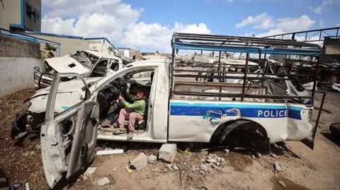 Displaced Palestinian children play inside a destroyed police car in a temporary camp within the site of the Arafat Police Academy, in the destroyed police camp affiliated with Hamas, in Gaza City (10 April 2025)
