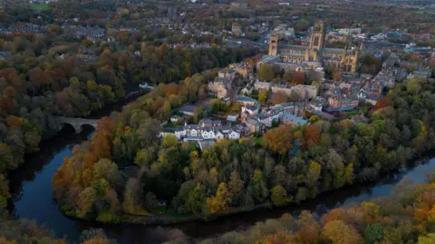 Reuters A view above Durham City. It shows Durham Cathedral, surrounded by houses and autumn leaves on the trees along the banks of the River Wear.