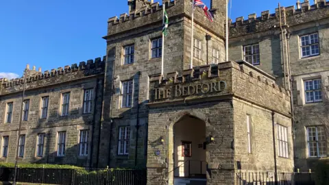 The Bedford Hotel The Bedford hotel frontage. The entrance sticks out and is made up of old stone blocks. There is a Devon flag and a Union Jack flying above the entrance.