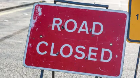 A red sign with "ROAD CLOSED" written in white capital letters.