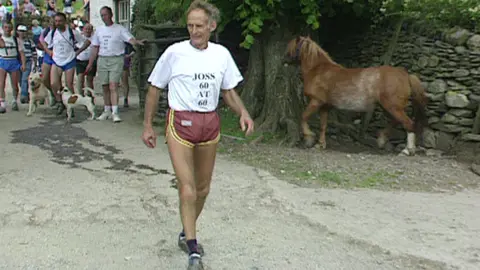 Mr Naylor walking on a countryside path after finishing a race. He is wearing a t-shirt which says 'Joss 60 at 60' 