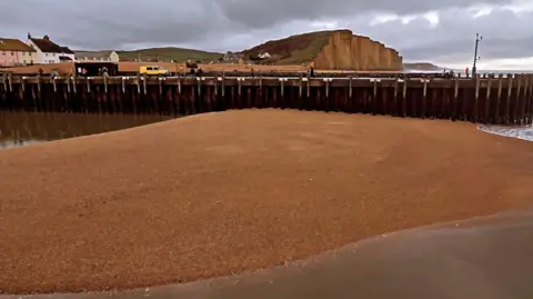 Ross Moore / Platform Restaurant A huge sand bar blocking the entrance to the harbour at West Bay with the cliffs in the background.