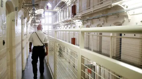 PA A prison officer walks in a prison