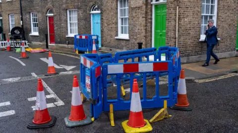 Cones surround a cordoned off area in the middle of a road in a residential street