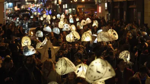 A large crowd of people carrying lit-up lanterns. 