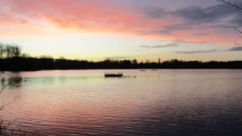 Peterborough Walks A pink and light-golden sky, with it reflected in the river beneath.