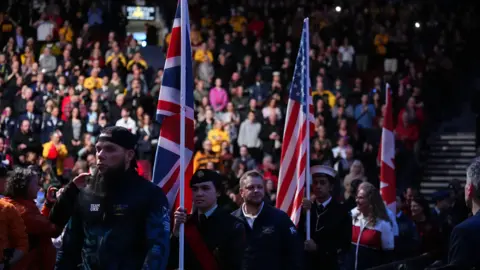 PA Tiga bendera Inggris, AS dan Kanada berparade pada upacara penutupan dengan kerumunan besar di latar belakang