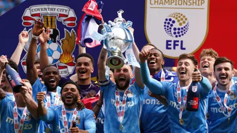 Coventry City captain Matt Grimes holds the Championship Trophy aloft during the on-pitch celebrations, after winning the title.