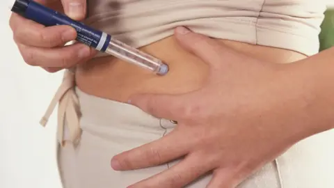 Getty Images Person injecting insulin in their abdomen - we do not see the needle but it involves a vial being pressed into the skin