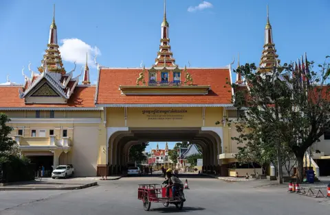Getty Images Thai and Cambodian workers ride motorcycles outside the Poipet Border Crossing, which is suspended due to the ongoing border conflict, in Poipet, Banteay Meanchey, Cambodia, on December 18, 2025.