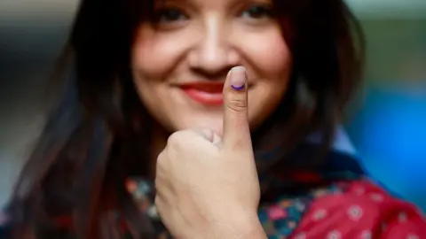 A voter shows her inked thumb after casting her ballot at a polling station during Nepal's parliamentary election in Kathmandu