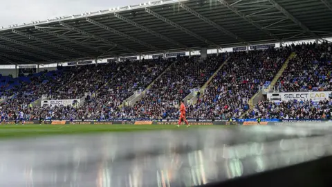 A general view of Select Car Leasing Stadium, home of Reading during the Sky Bet League One match between Reading FC and Lincoln City FC - a goalkeeper in orange can be seen on the pitch with stands full of supporters in the background