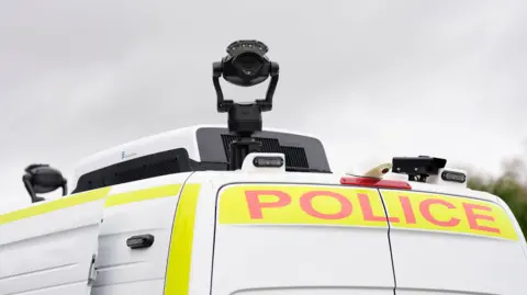 PA Media Top of a white police van with a black camera attached on it.