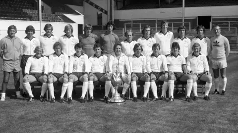 Press Association The Derby County squad that won the First Division in 1974/75 pictured on a football pitch with the league trophy. 