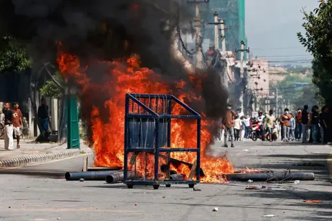 AFP via Getty Images A police barricade is pictured in front of a fire set alight by demonstrators during a protest outside the Parliament in Kathmandu