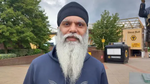 BBC Manny Singh Kang wearing a blue top, with a long beard, standing near Molineux
