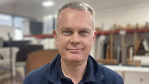 Lee Wright, who has grey hair and blue eyes. Mr Wright is wearing a blue jumper in the photo.