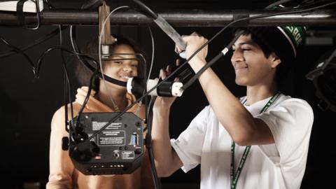 Two students adjusting backstage equipment