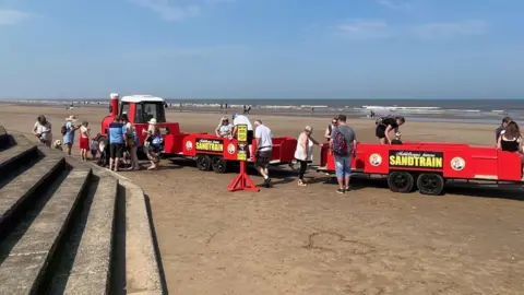 BBC / Kevin Shoesmith Passengers alight a red sand train on Mablethorpe beach