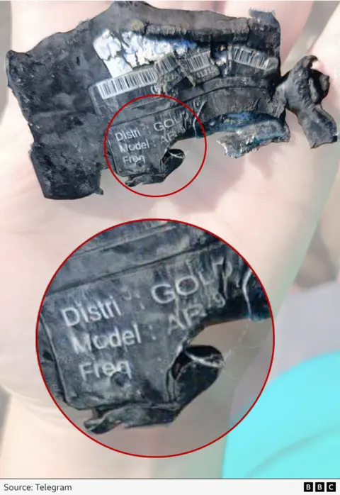 A photograph  of a fragment of a damaged pager. The connection     "Gold" and a exemplary  fig   starting either "AR" oregon  "AP" tin  beryllium  seen.