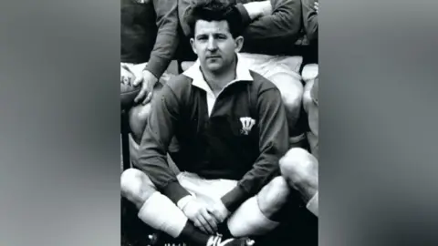 Bryan Richards sits cross legged in his Wales shirt 