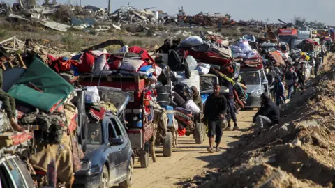 Reuters mengungsi dari antrian Palestina untuk mendapatkan kendaraan dan gerobak keledai mereka diperiksa di pos pemeriksaan di jalan menuju Gaza utara (27 Januari 2025)