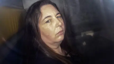 Erin Patterson, looking at the camera in the back of a prison van